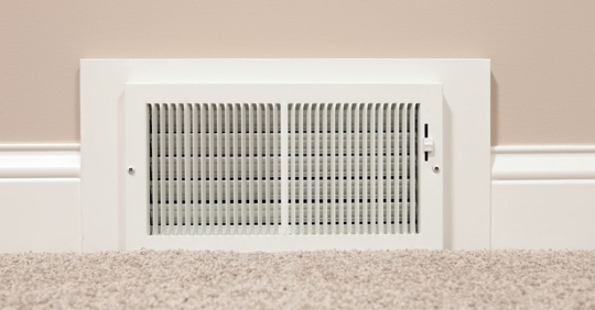 White vent on the bottom of the floor near beige carpet and wall