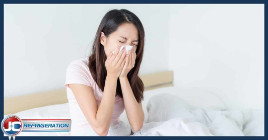A woman blowing her nose in bed