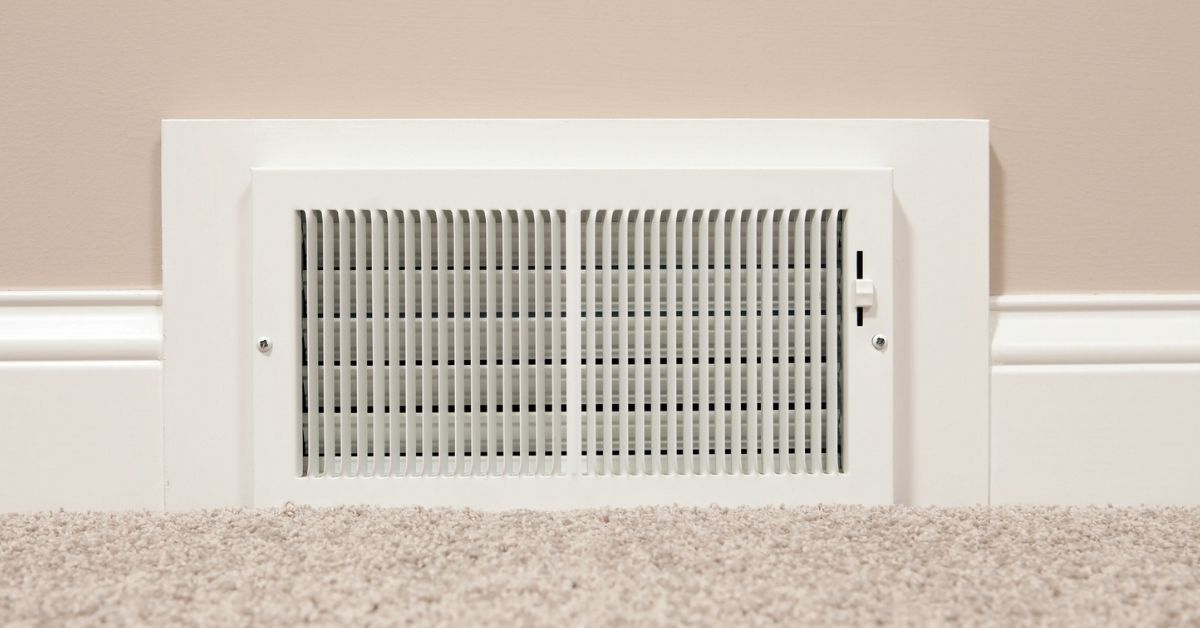 White vent on the bottom of the floor near beige carpet and wall